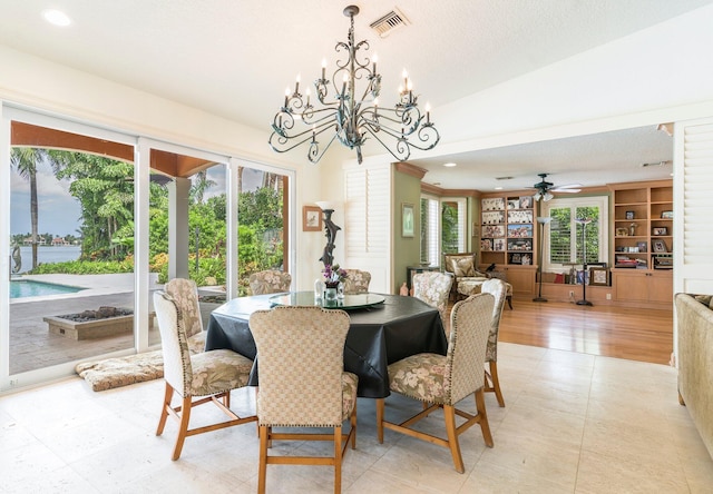 dining room with vaulted ceiling, a healthy amount of sunlight, ceiling fan with notable chandelier, and light wood-type flooring