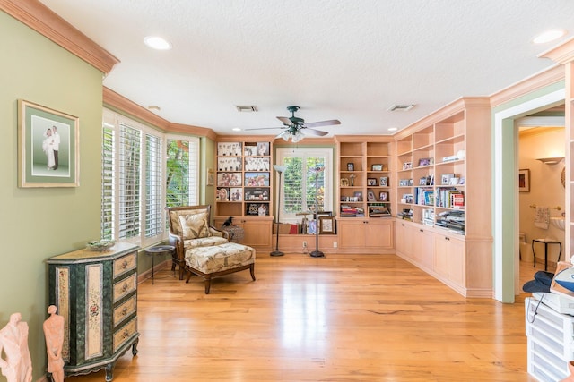 sitting room with plenty of natural light, light hardwood / wood-style floors, a textured ceiling, and ornamental molding