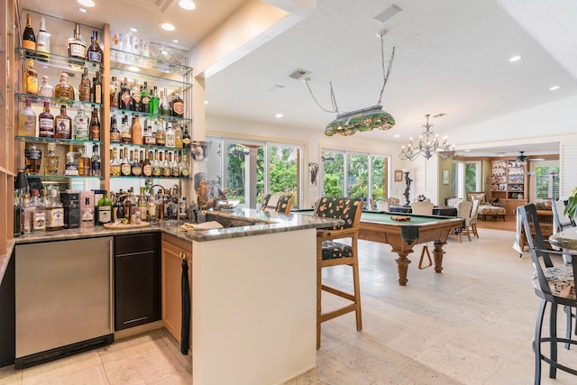 bar featuring dark stone countertops, stainless steel fridge, a textured ceiling, and billiards