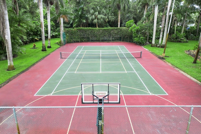 view of tennis court with basketball hoop and a yard