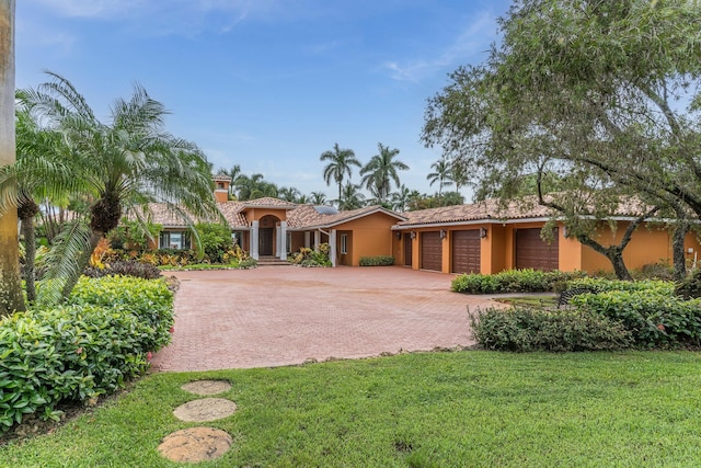 mediterranean / spanish home with a garage and a front lawn