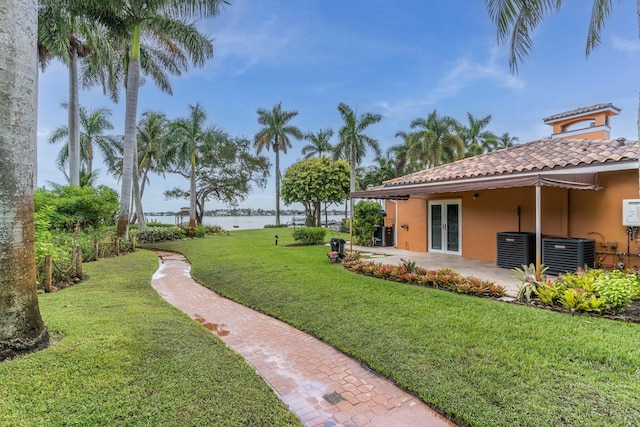 view of yard with french doors, a patio, a water view, and central AC