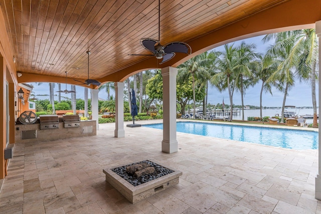 view of pool featuring a fire pit, exterior kitchen, a patio, and grilling area