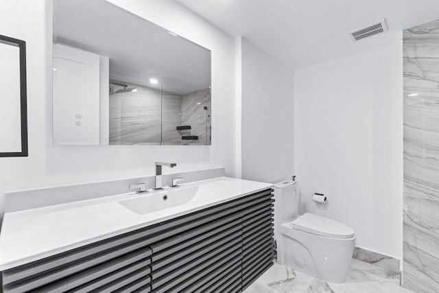 bathroom featuring vanity, tiled shower, and toilet