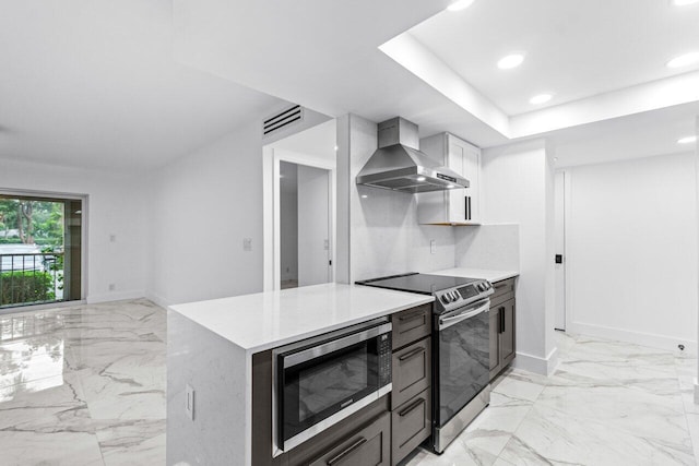 kitchen featuring wall chimney exhaust hood, stainless steel appliances, backsplash, white cabinetry, and light stone counters