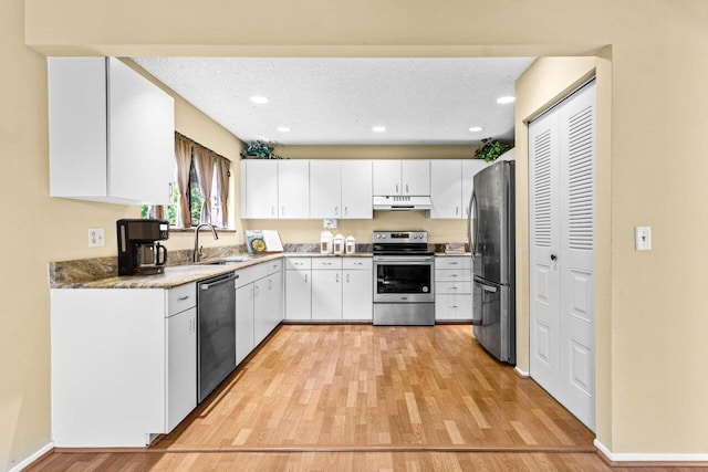 kitchen featuring appliances with stainless steel finishes, light hardwood / wood-style floors, sink, and white cabinets