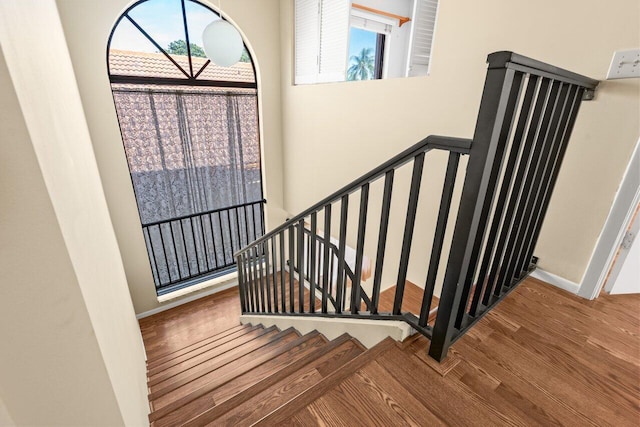 staircase with hardwood / wood-style flooring and a high ceiling