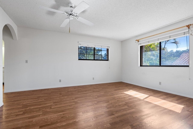 empty room featuring dark hardwood / wood-style flooring, ceiling fan, and a textured ceiling