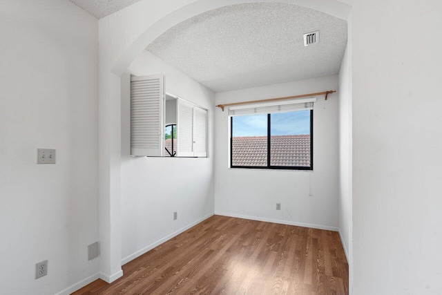 spare room featuring hardwood / wood-style floors and a textured ceiling