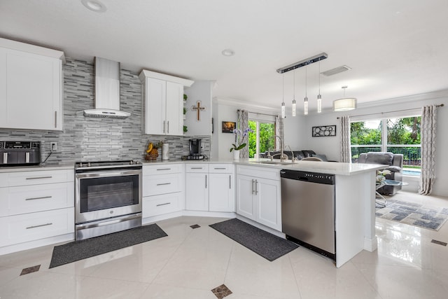 kitchen with appliances with stainless steel finishes, white cabinetry, a healthy amount of sunlight, and wall chimney range hood