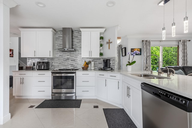 kitchen featuring appliances with stainless steel finishes, white cabinetry, wall chimney exhaust hood, decorative light fixtures, and crown molding