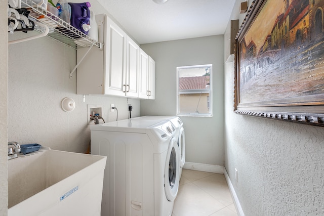 laundry area with sink, washer and dryer, light tile patterned floors, and cabinets