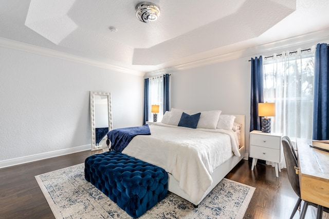 bedroom featuring dark wood-type flooring, a raised ceiling, and ornamental molding