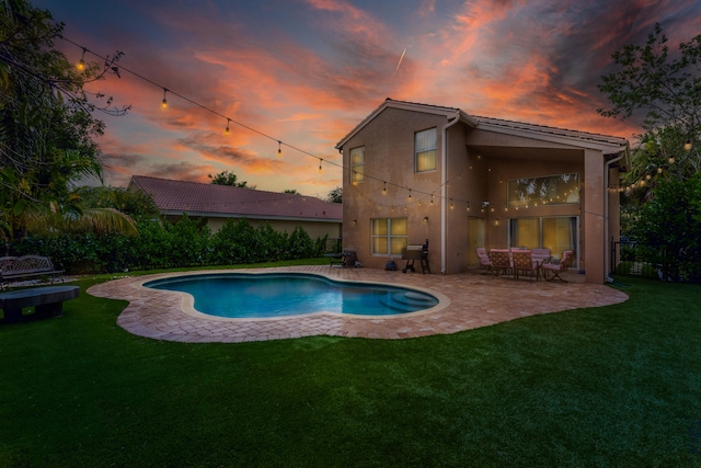 pool at dusk featuring a patio area and a lawn