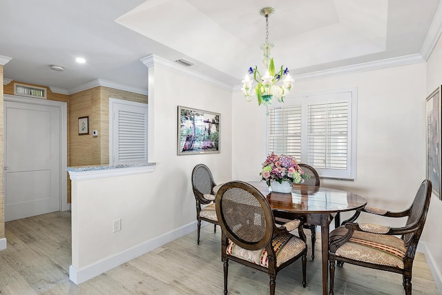 dining room featuring a notable chandelier, a tray ceiling, light hardwood / wood-style flooring, and ornamental molding