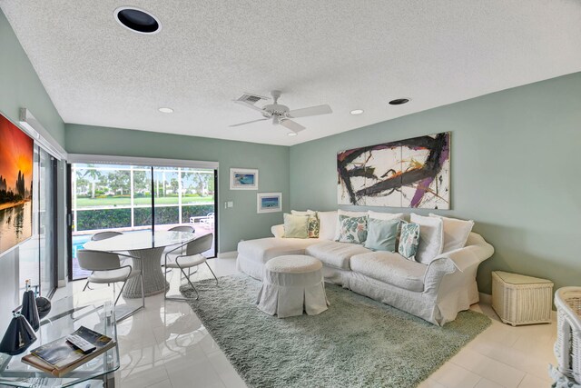 tiled living room with a textured ceiling and ceiling fan