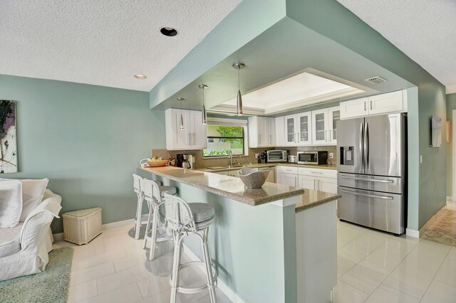 kitchen with white cabinetry, stainless steel appliances, sink, and a raised ceiling