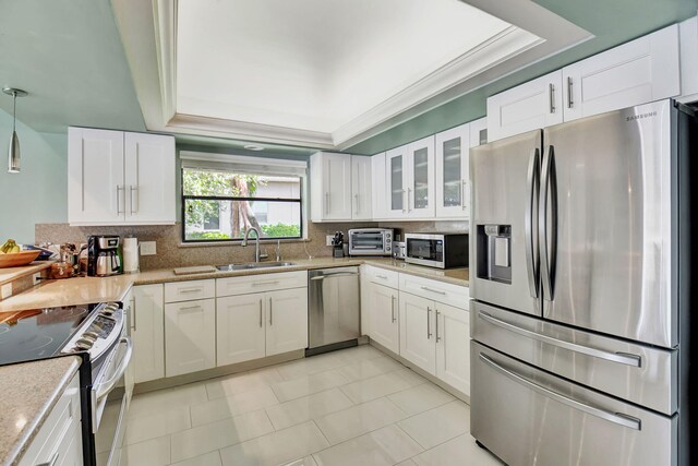 kitchen with light stone counters, stainless steel appliances, hanging light fixtures, sink, and white cabinets