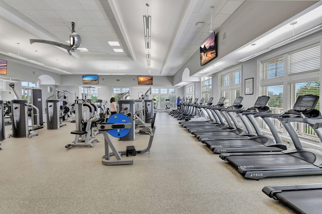 exercise room with a high ceiling and ceiling fan