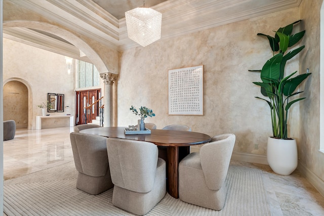 dining space with a towering ceiling, ornamental molding, a chandelier, and ornate columns