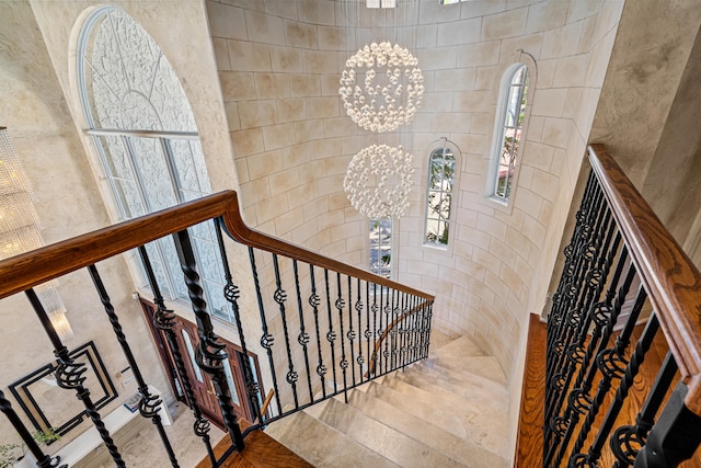 staircase with an inviting chandelier and a high ceiling