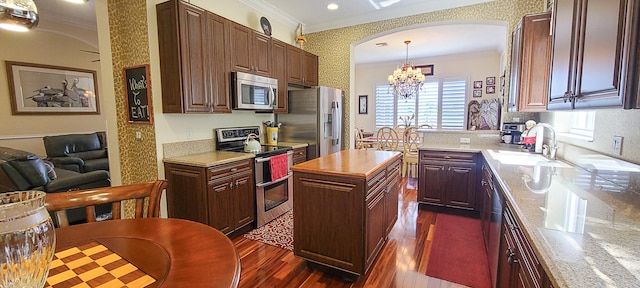 kitchen with sink, stainless steel appliances, dark hardwood / wood-style flooring, a kitchen island, and ornamental molding