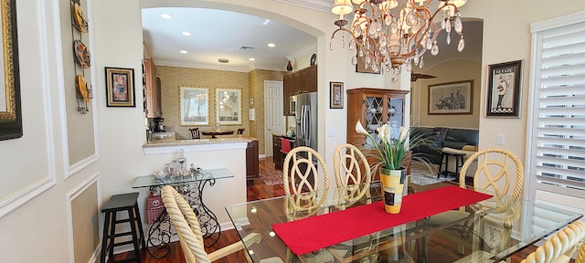 dining room with plenty of natural light, dark hardwood / wood-style flooring, ornamental molding, and an inviting chandelier