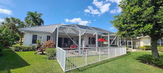 back of house featuring a lanai and a lawn