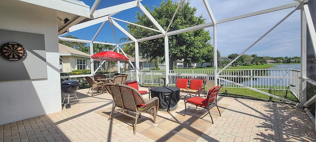 view of patio featuring a water view and glass enclosure