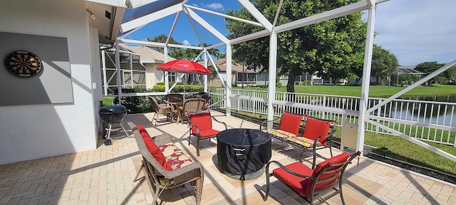 view of patio / terrace featuring a lanai and a water view