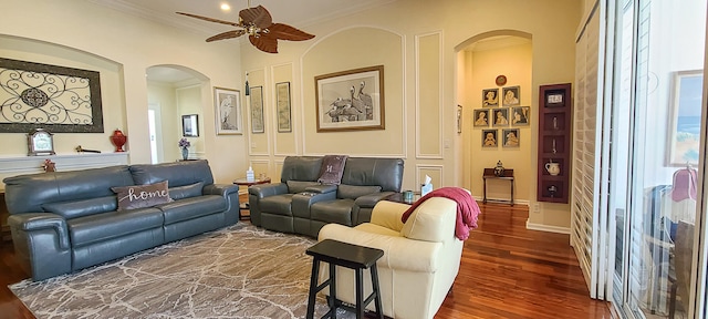 living room with crown molding, ceiling fan, and dark wood-type flooring