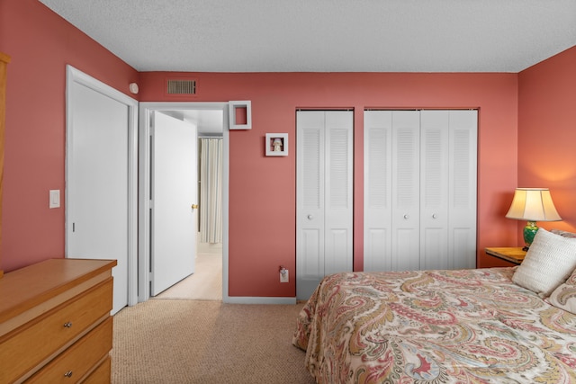 carpeted bedroom with multiple closets and a textured ceiling