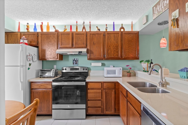 kitchen featuring light tile patterned flooring, hanging light fixtures, sink, a textured ceiling, and stainless steel appliances