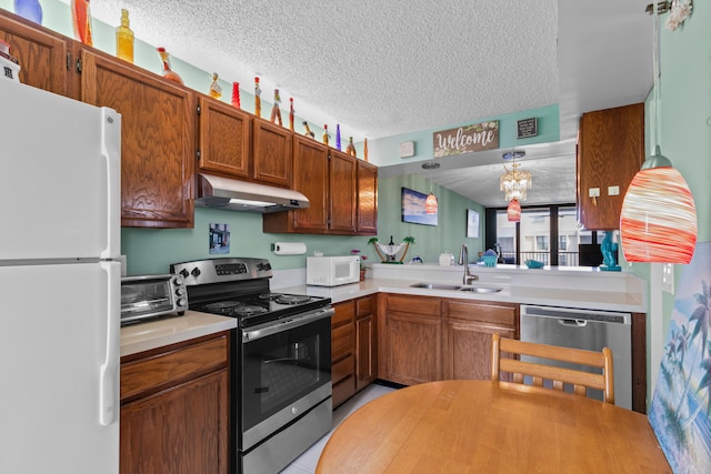 kitchen with pendant lighting, sink, a textured ceiling, stainless steel appliances, and a notable chandelier