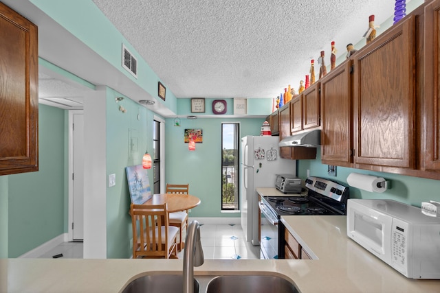 kitchen featuring light tile patterned floors, sink, kitchen peninsula, stainless steel electric range, and a textured ceiling