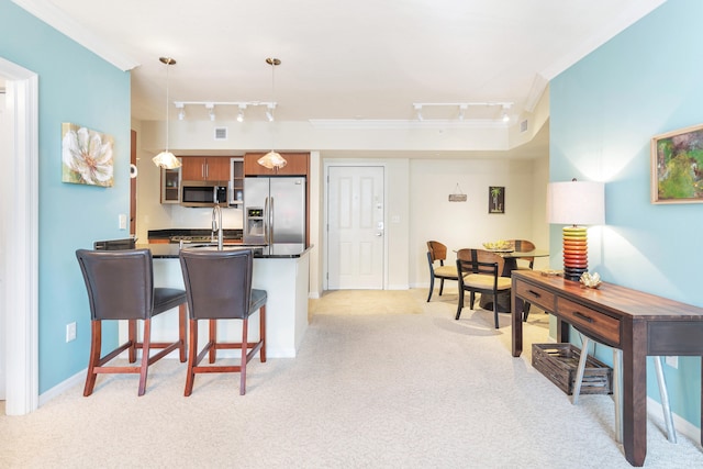 kitchen featuring appliances with stainless steel finishes, track lighting, light colored carpet, and a kitchen breakfast bar