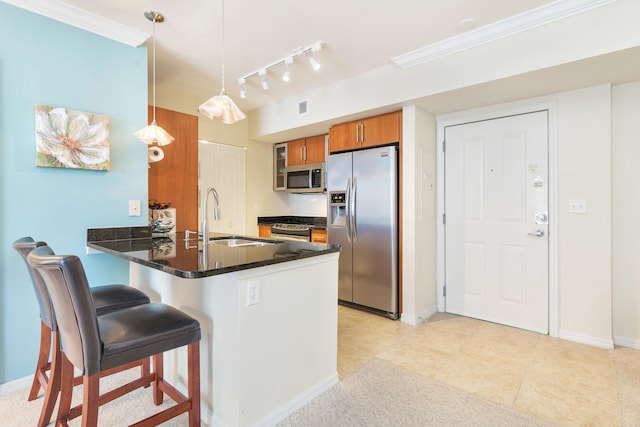 kitchen featuring appliances with stainless steel finishes, sink, kitchen peninsula, pendant lighting, and a breakfast bar area