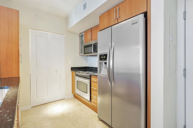 kitchen with appliances with stainless steel finishes and dark stone countertops