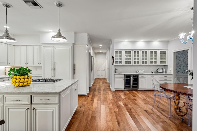 kitchen featuring white cabinets, wine cooler, light wood-type flooring, and decorative light fixtures