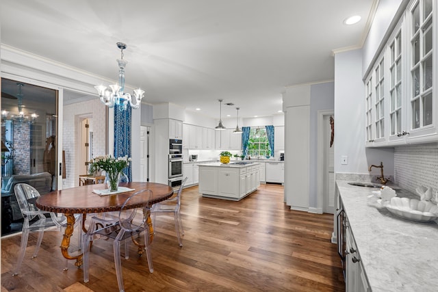 dining area with a chandelier, sink, hardwood / wood-style flooring, and crown molding