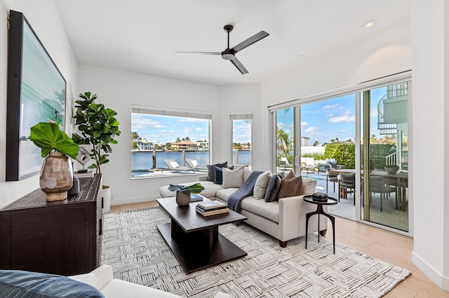 living room featuring a water view, light hardwood / wood-style floors, and ceiling fan