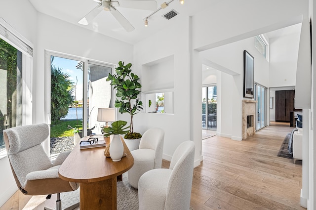 dining area with light hardwood / wood-style floors, a high ceiling, plenty of natural light, and ceiling fan