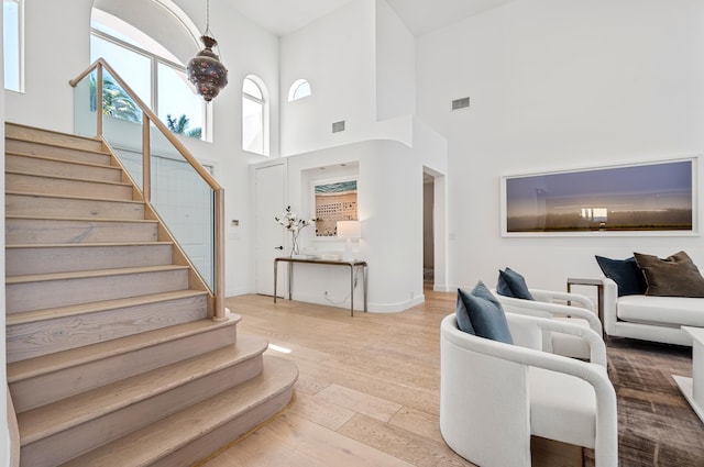 living room with hardwood / wood-style flooring, a high ceiling, and a wealth of natural light