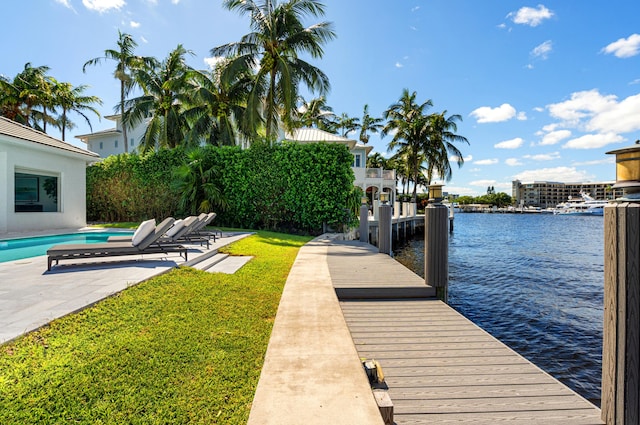 view of dock featuring a water view, a patio area, and a lawn