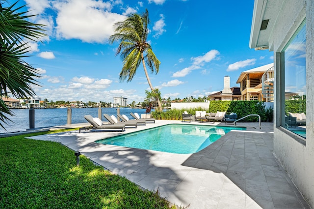 view of swimming pool with a patio, a water view, and a lawn