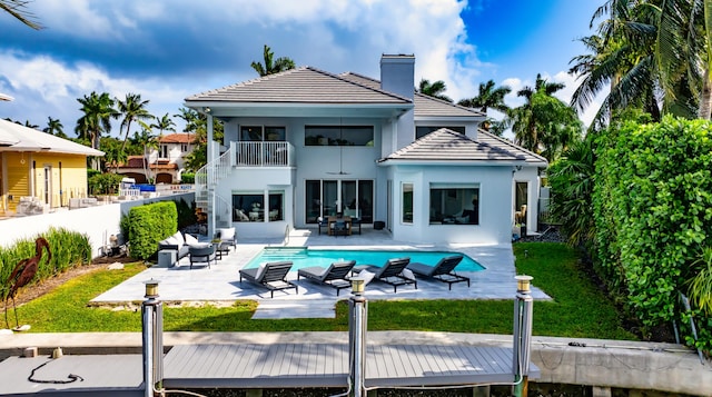 rear view of property featuring a patio, ceiling fan, a lawn, and a balcony