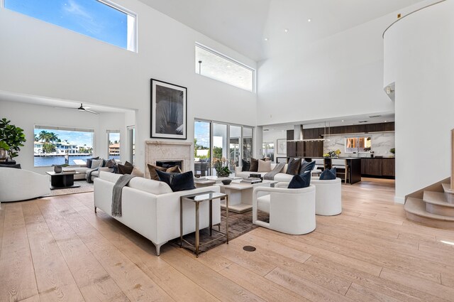 1026 Seasage Dr, Delray Beach, FL 33483 - living area featuring a towering ceiling, light wood-style flooring, a fireplace, plenty of natural light, and a ceiling fan