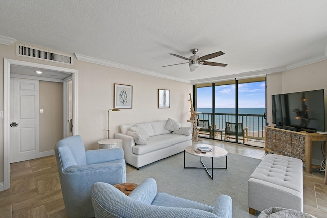 living room featuring ornamental molding, ceiling fan, expansive windows, and a textured ceiling