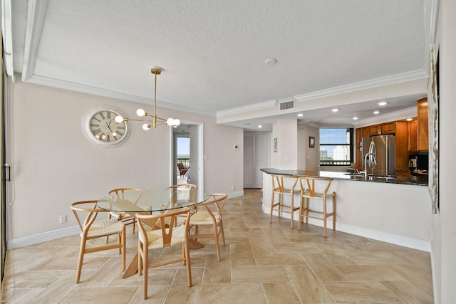 dining room with sink, crown molding, a notable chandelier, and a textured ceiling