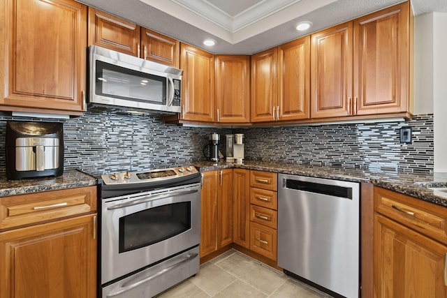 kitchen with appliances with stainless steel finishes, backsplash, ornamental molding, and dark stone counters